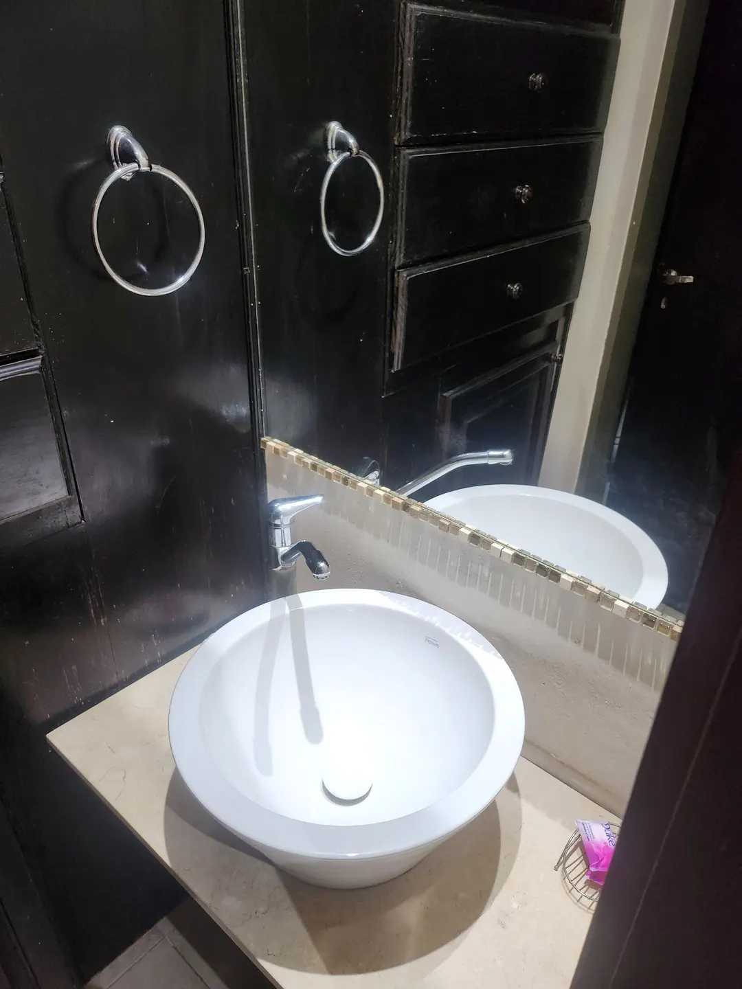 Lavabo redondo blanco, espejo y mueble de madera oscura