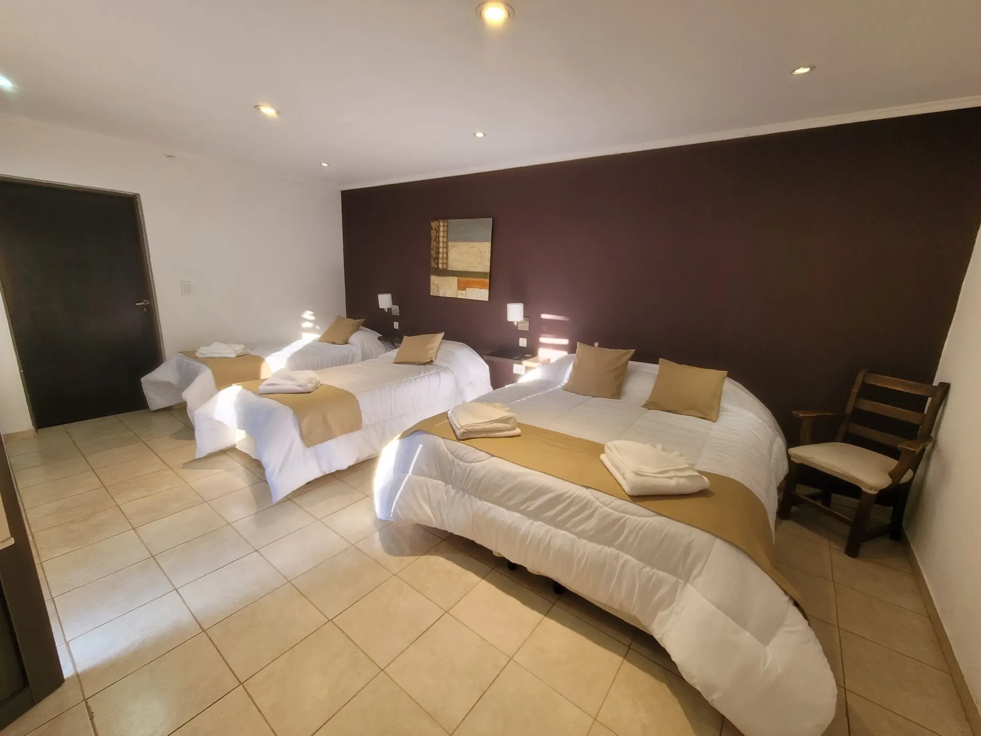 Habitación con una cama matrimonial, dos individuales y una cuna junto a la pared oscura